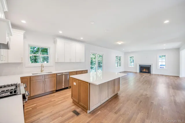 a large kitchen with stainless steel appliances granite countertop a sink dishwasher a stove and a refrigerator with wooden floor