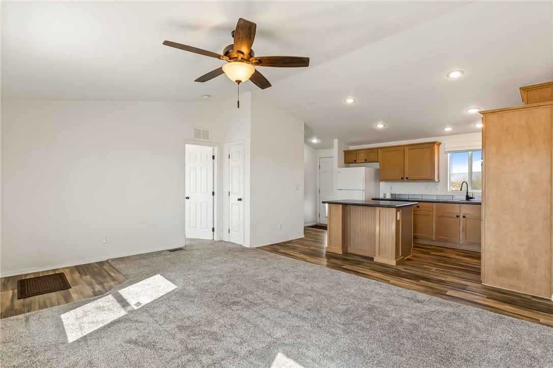 3534 Eloy Road Golden Valley, AZ 86413 - Photo 11 of 58 Kitchen featuring dark countertops, vaulted ceiling, dark carpet, a kitchen island, and freestanding refrigerator