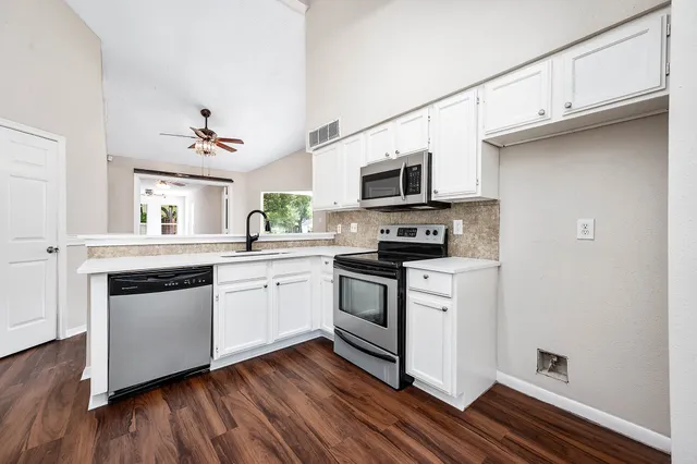 a kitchen with cabinets stainless steel appliances a sink and a window