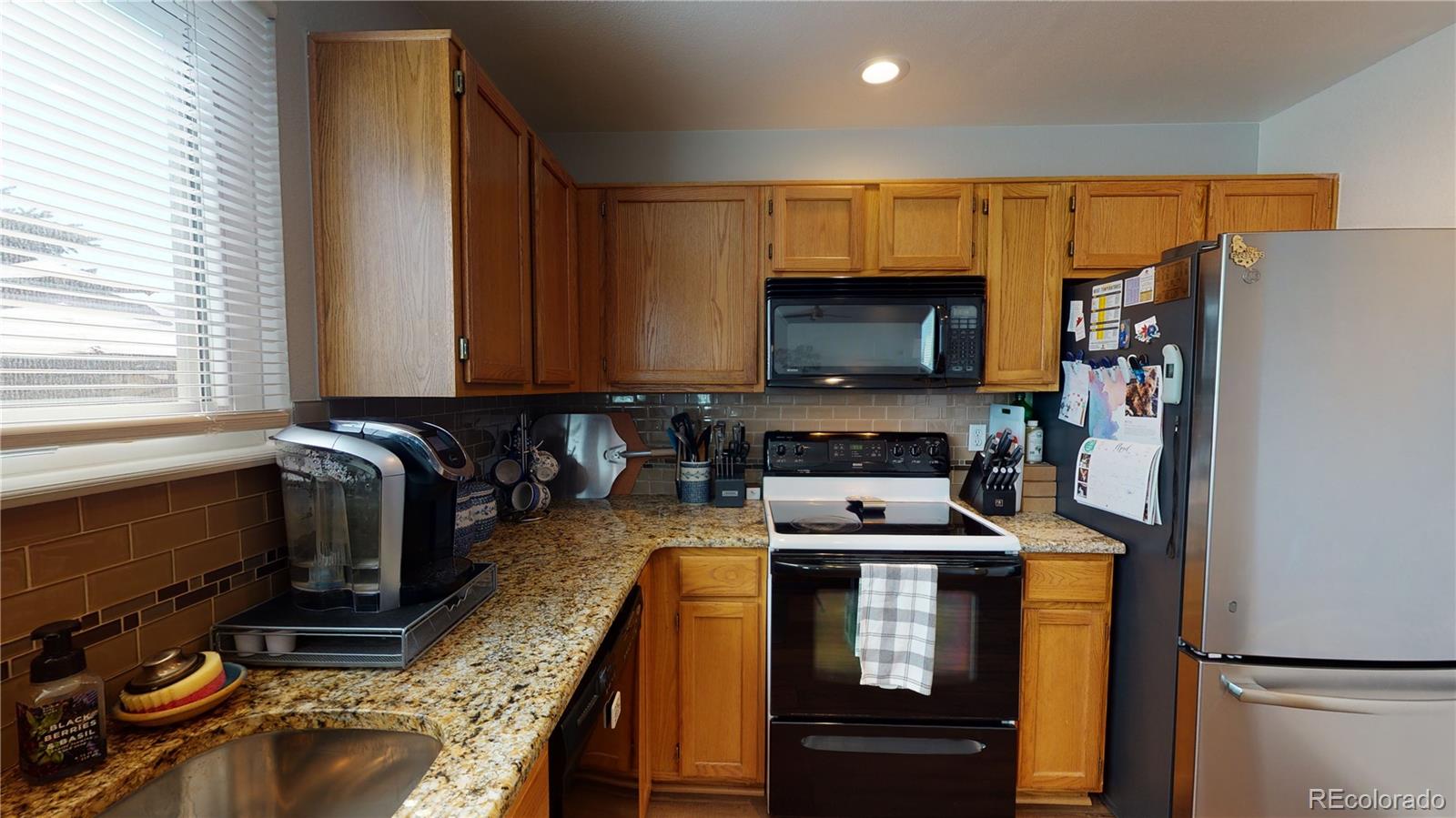 10482 Hyacinth Street Highlands Ranch, CO 80129 - Photo 13 of 40 a kitchen with granite countertop a refrigerator stove and microwave