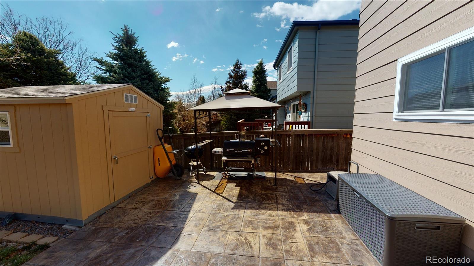 10482 Hyacinth Street Highlands Ranch, CO 80129 - Photo 37 of 40 a view of a patio with table and chairs under an umbrella with wooden floor