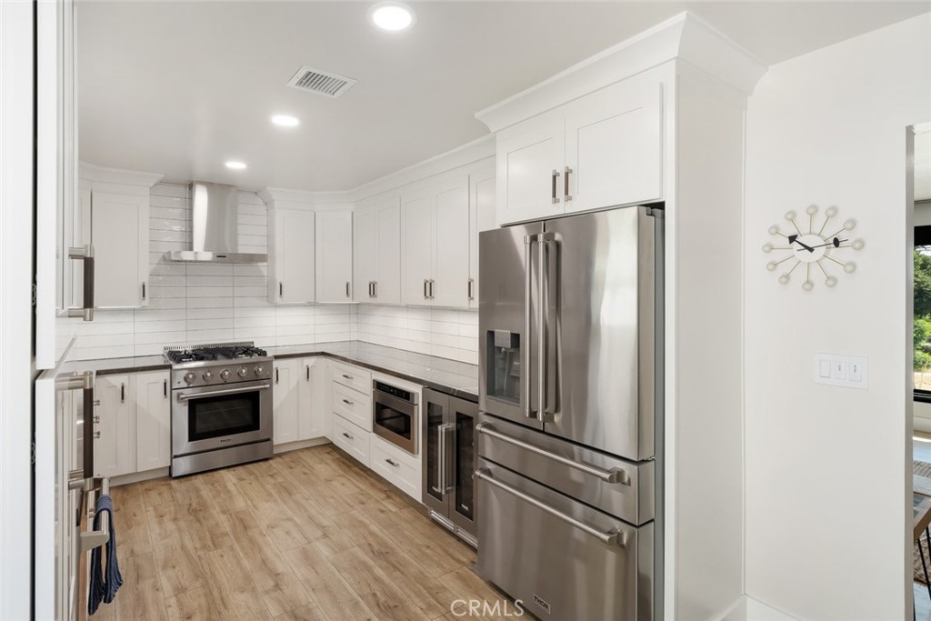 905 Olive Street Paso Robles, CA 93446 - Photo 13 of 61 a kitchen with stainless steel appliances white cabinets and wooden floor