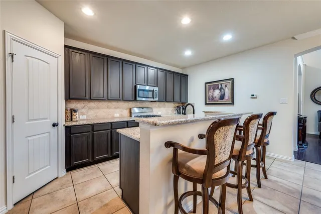 a kitchen with stainless steel appliances granite countertop a stove a sink a refrigerator with a dining table and chairs