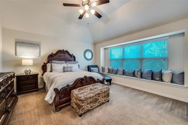 a bedroom with a large bed and a chandelier fan