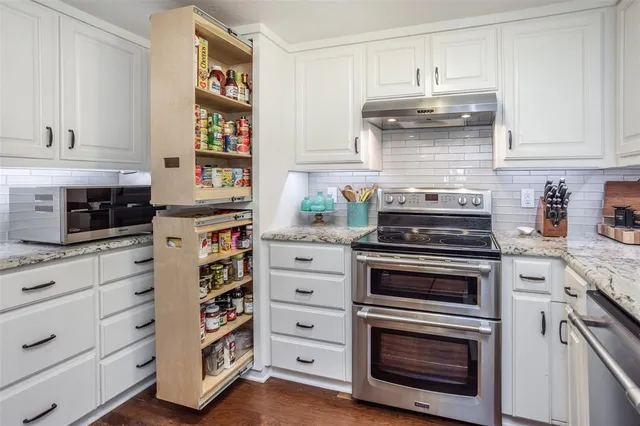 a kitchen with granite countertop white cabinets and stainless steel appliances