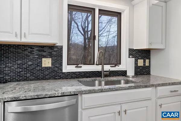 a kitchen with granite countertop white cabinets and sink
