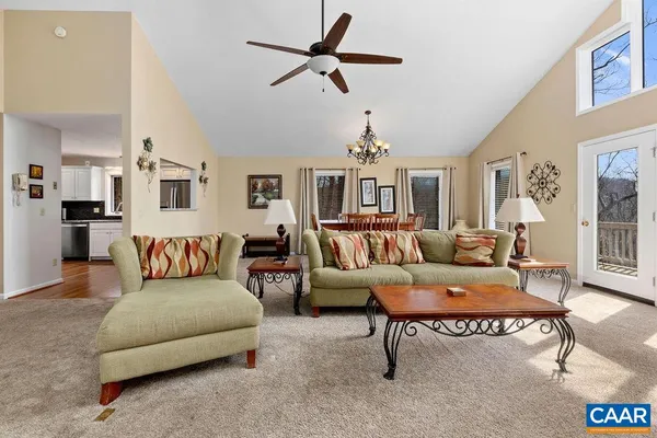 a living room with furniture kitchen view and a chandelier