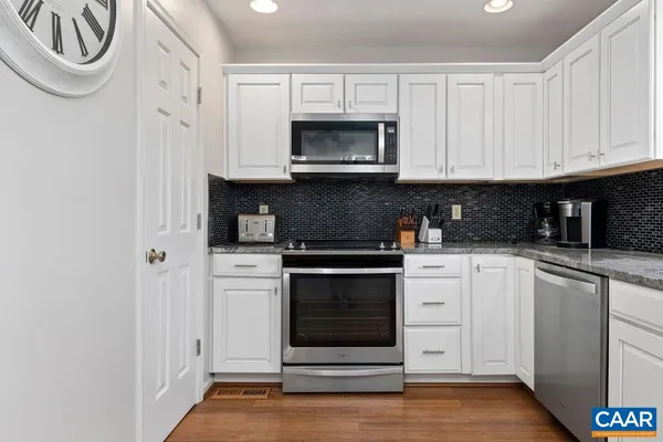 a kitchen with granite countertop white cabinets and stainless steel appliances