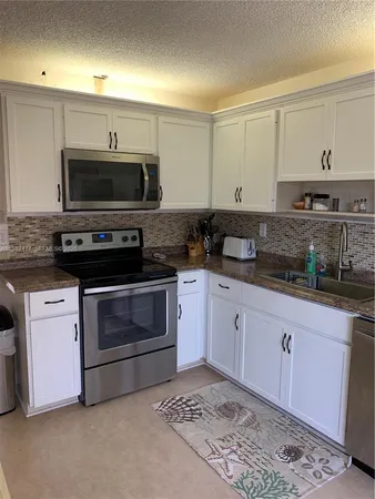 a kitchen with granite countertop a stove a sink and a microwave