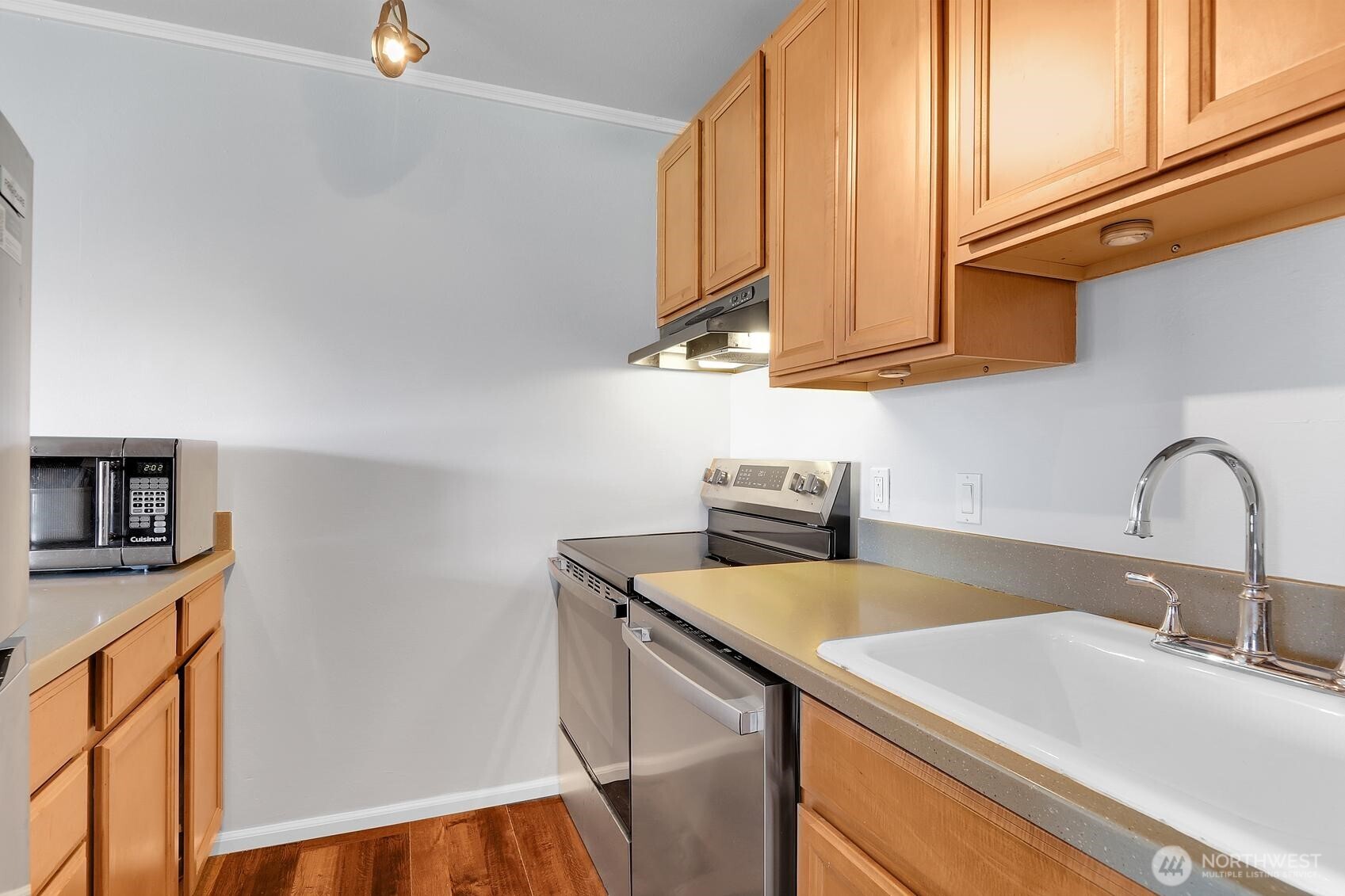 7924 212th Street Southwest, Unit 211 Edmonds, WA 98026 - Photo 7 of 14 a kitchen with stainless steel appliances a sink a stove and a microwave with wooden floor