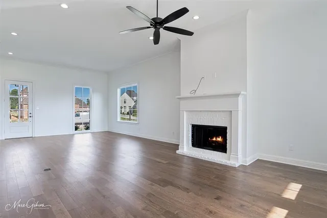 an empty room with windows fireplace and wooden floor