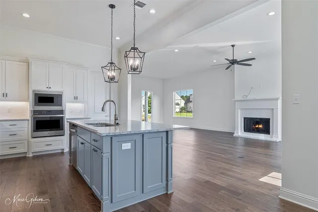 a kitchen with stainless steel appliances granite countertop a sink a stove and a wooden floor