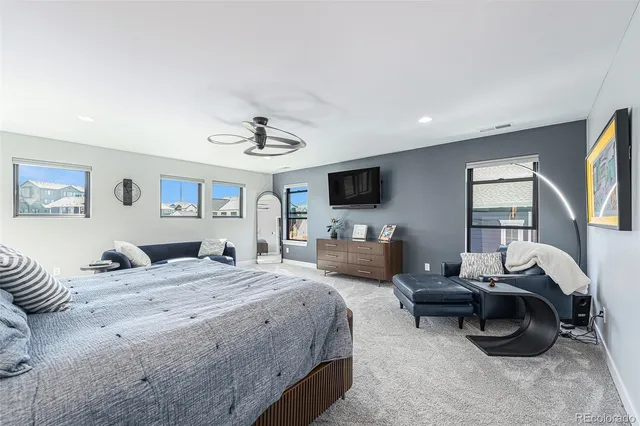 a spacious bedroom with a bed a couch and a flat screen tv