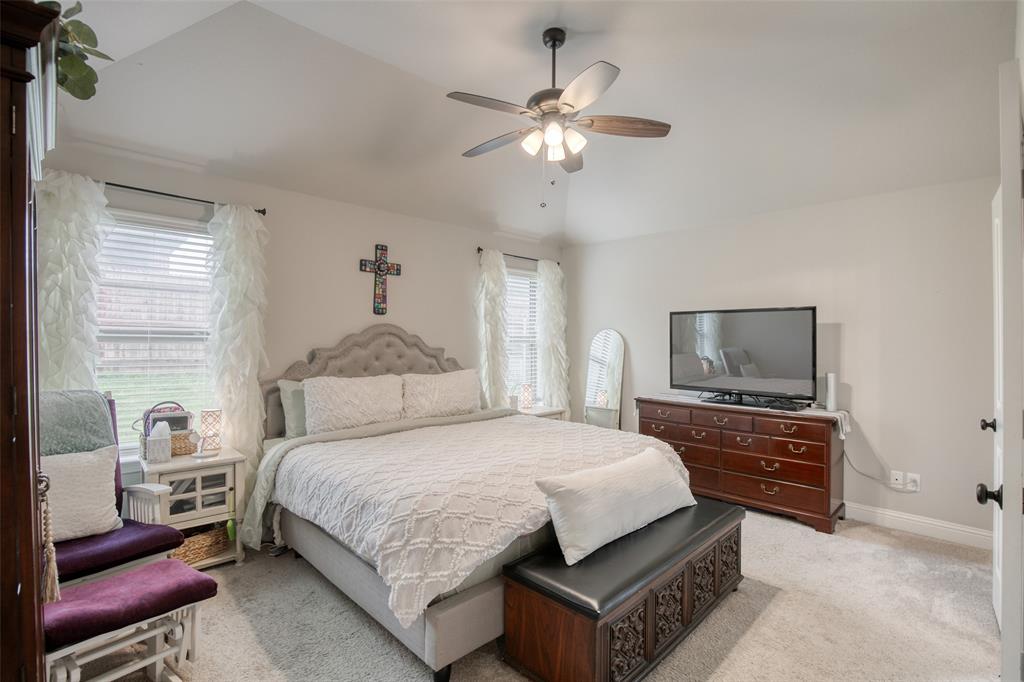 211 Rees Avenue Godley, TX 76044 - Photo 10 of 18 a bedroom with a large bed a chandelier and a dresser