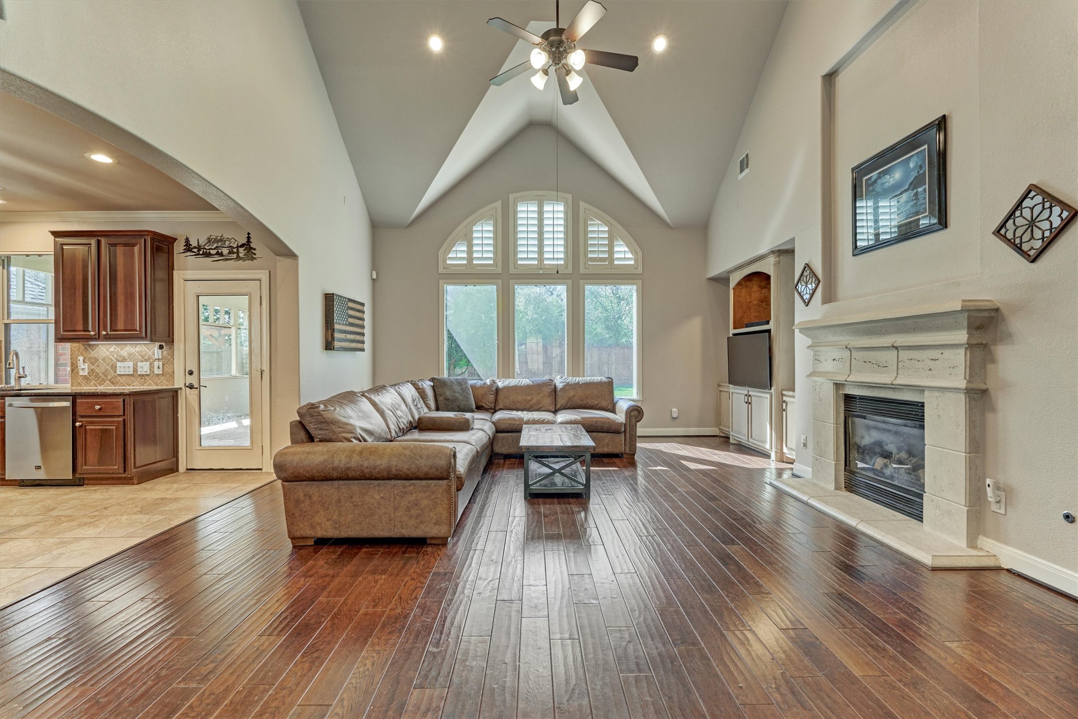 6615 Pelham Chase Drive Spring, TX 77389 - Photo 12 of 49 The living room features high ceilings, neutral finishes and a unique vault at the arched window for a unique architectural detail. The wood flooring continues throughout this space for a cohesive look. The kitchen is to the left in this photo.