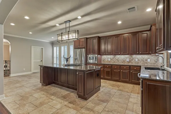 a kitchen with stainless steel appliances granite countertop wooden cabinets a stove top oven a sink and dishwasher