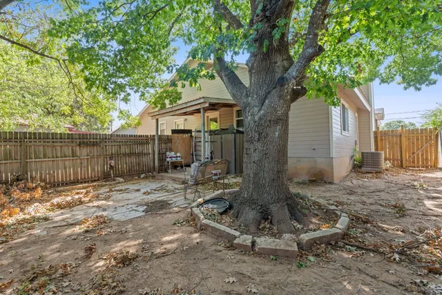 a view of backyard with wooden fence and a large tree