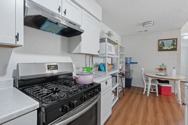 a kitchen with a stove a chimney cabinets and a counter space