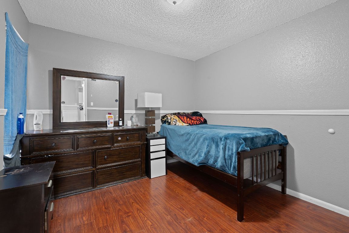 1105 Quail Valley Drive Georgetown, TX 78626 - Photo 32 of 38 a bedroom with a bed and dresser with wooden floor