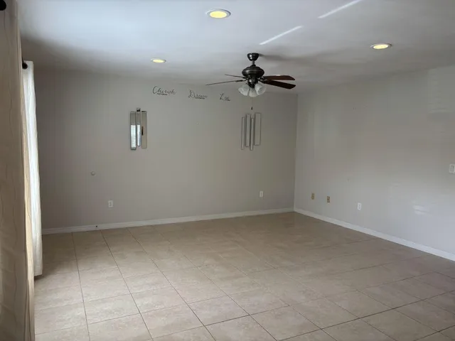 an empty room with a ceiling fan and carpet