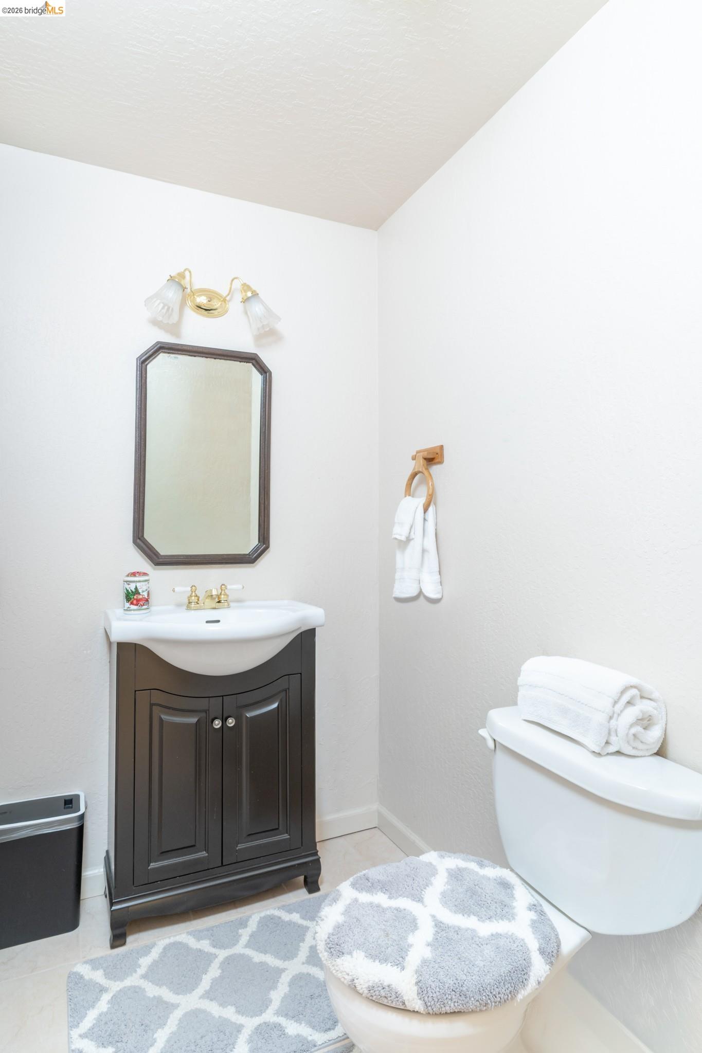 19390 Ferretti Road Groveland, CA 95321 - Photo 23 of 38 Dark wood-finish vanity with an integrated sink, gold-tone faucet, and an octagonal framed mirror