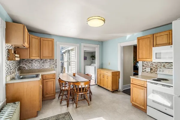a kitchen that has a lot of white cabinets and stainless steel appliances