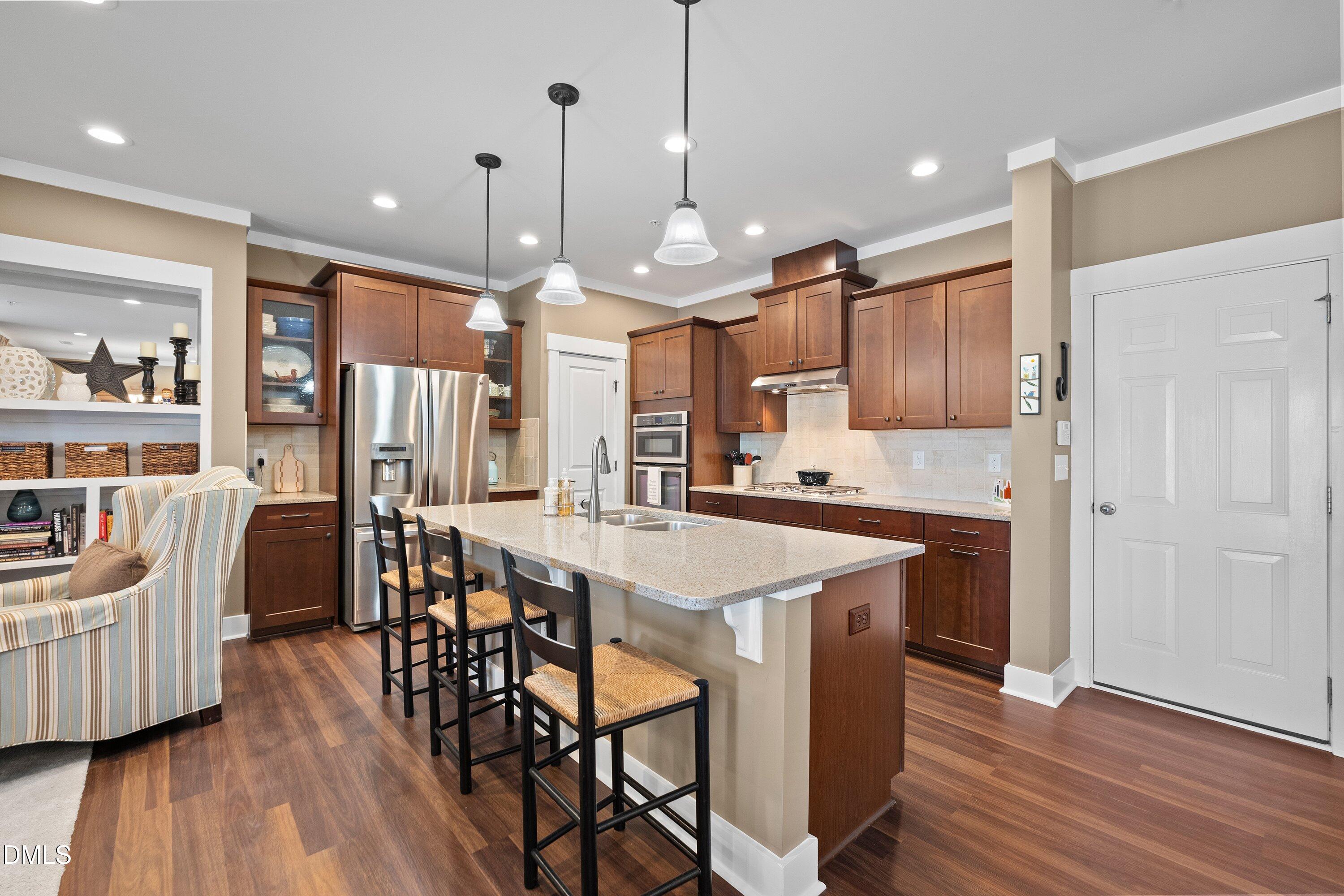 9302 Alcazar Walk Raleigh, NC 27617 - Photo 7 of 40 a kitchen with stainless steel appliances a dining table chairs stove and wooden floor