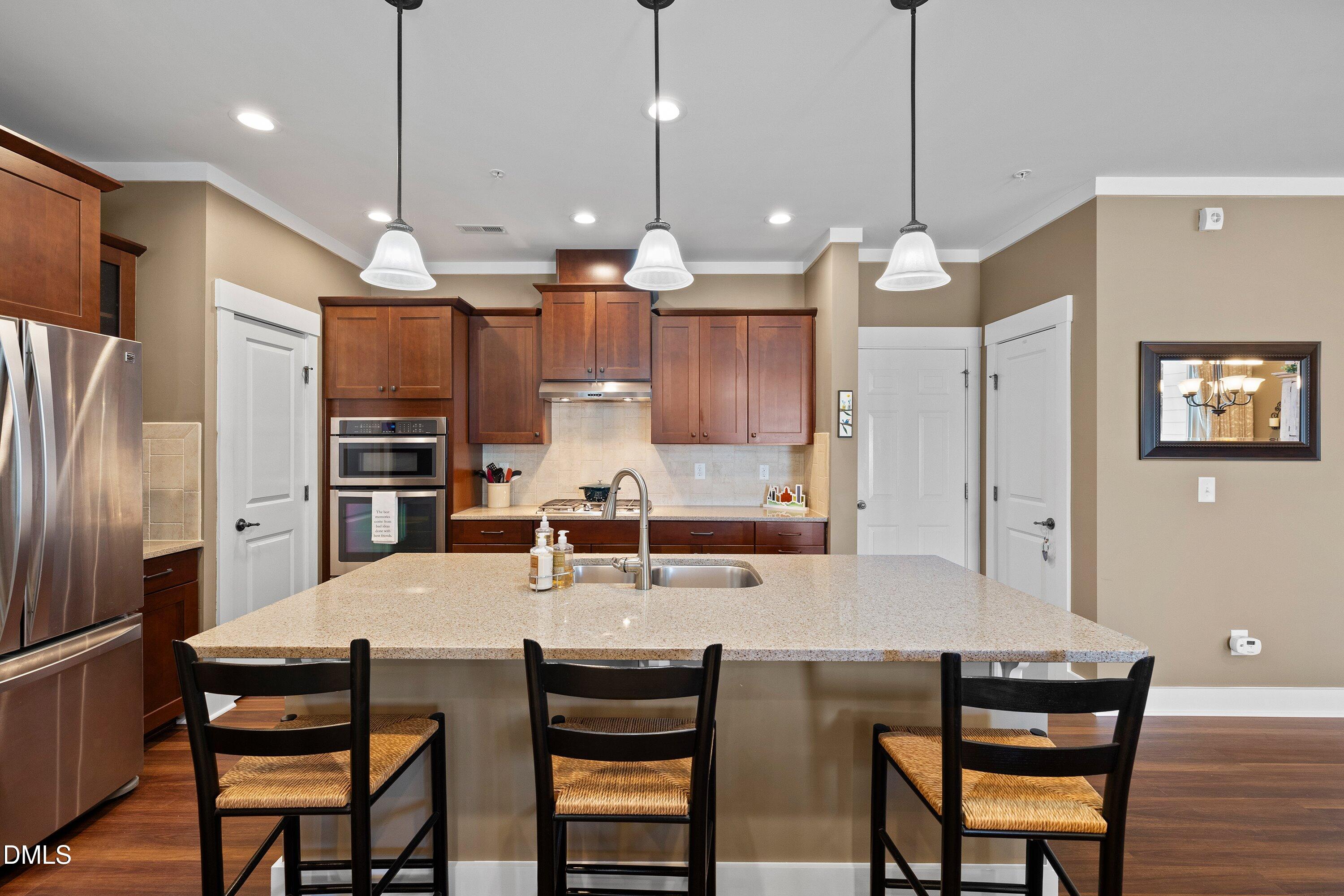 9302 Alcazar Walk Raleigh, NC 27617 - Photo 8 of 40 a kitchen with stainless steel appliances kitchen island granite countertop a dining table chairs and a refrigerator