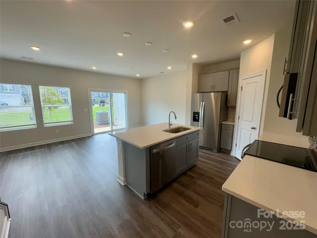 a kitchen with stainless steel appliances granite countertop a refrigerator a sink dishwasher a stove and a refrigerator with wooden floor