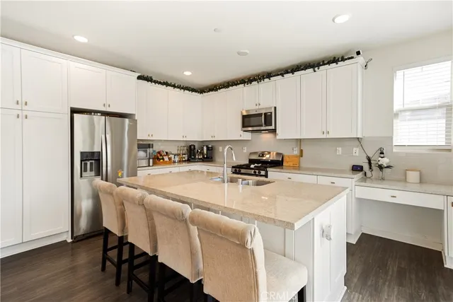 a kitchen with stainless steel appliances granite countertop a stove top oven a sink dishwasher a dining table and chairs with wooden floor