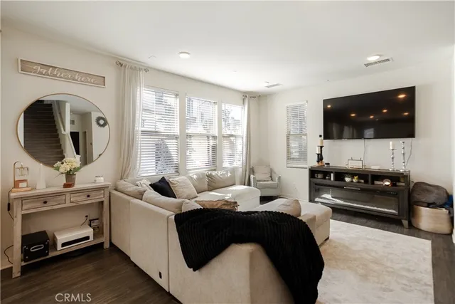 a living room with furniture and kitchen view with wooden floor