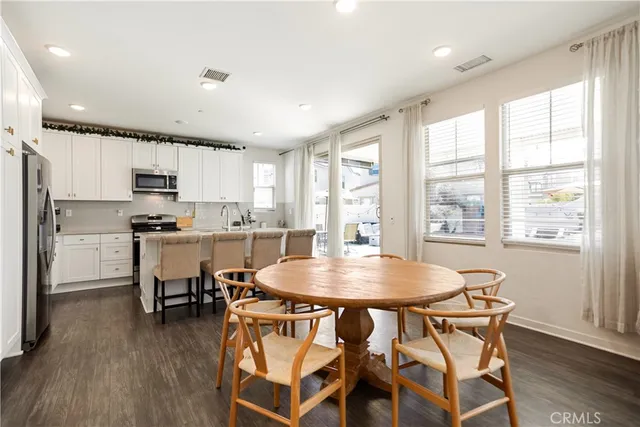 a kitchen with stainless steel appliances kitchen island granite countertop a dining table chairs and sink