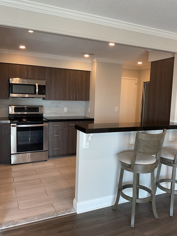 1006 Paradise Road, Unit PH Q Swampscott, MA 01907 - Photo 4 of 16 a kitchen with stainless steel appliances kitchen island granite countertop a table chairs microwave and sink