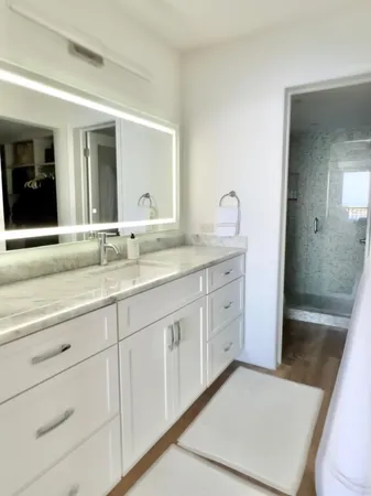 a bathroom with a granite countertop sink a mirror and bathtub