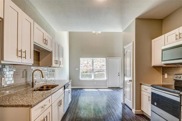 a kitchen with stainless steel appliances granite countertop a sink stove and microwave