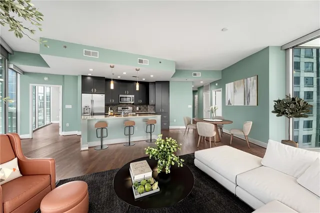 a living room with furniture a chandelier and kitchen view