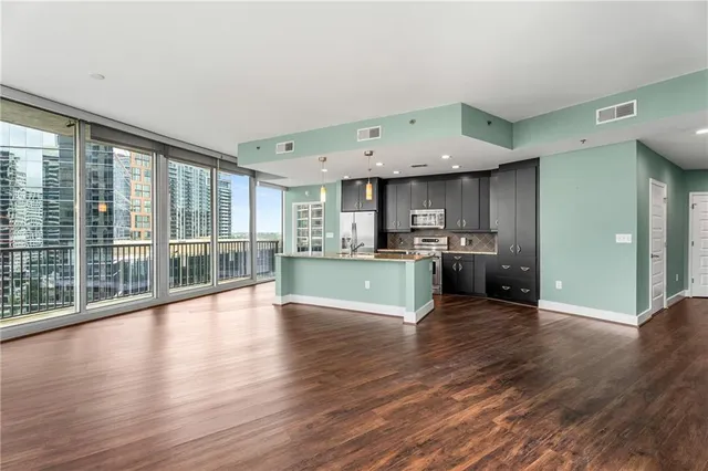 a view of a kitchen with kitchen island a sink wooden floor and a large window