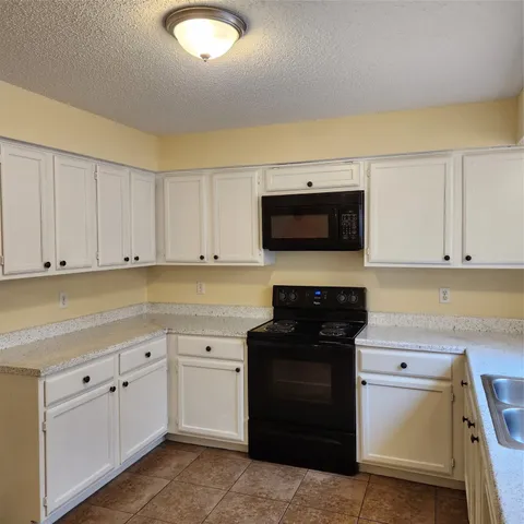 a kitchen with white cabinets and black appliances