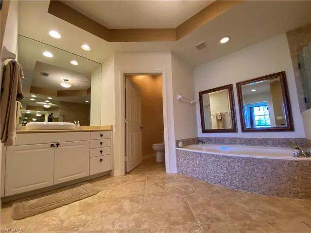 a view of an empty room and bathroom with mirror