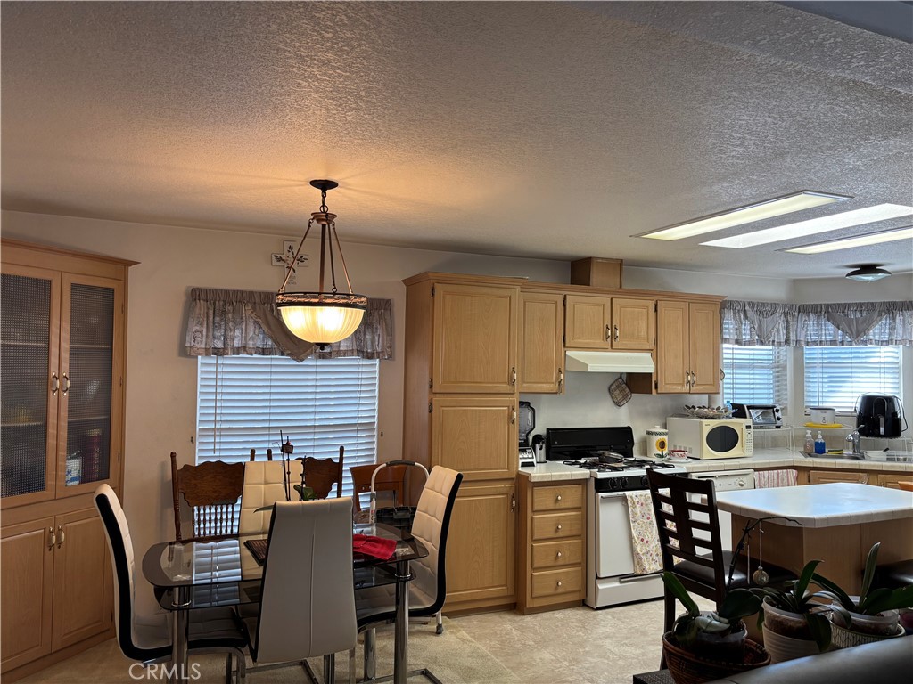 8389 Baker Avenue, Unit 82 Rancho Cucamonga, CA 91730 - Photo 5 of 13 a kitchen with a table chairs a sink dishwasher and cabinets