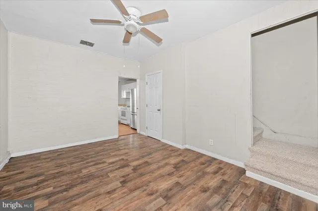 an empty room with wooden floor fan and windows