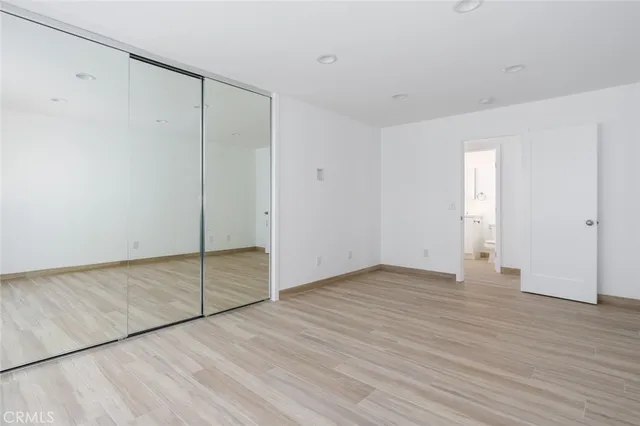 a view of an empty room with closet and wooden floor