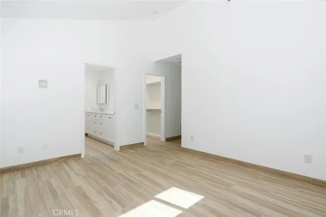 a view of an empty room with wooden floor and a sink