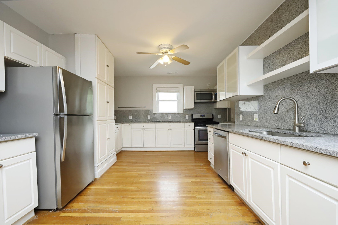 Undisclosed Address Raleigh, NC 27605 - Photo 4 of 38 a kitchen with granite countertop a refrigerator oven a sink dishwasher and white cabinets with wooden floor