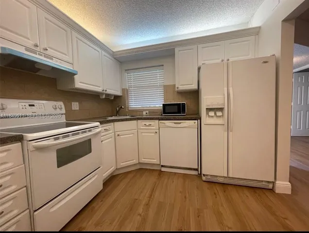 a kitchen with cabinets appliances wooden floor and a window