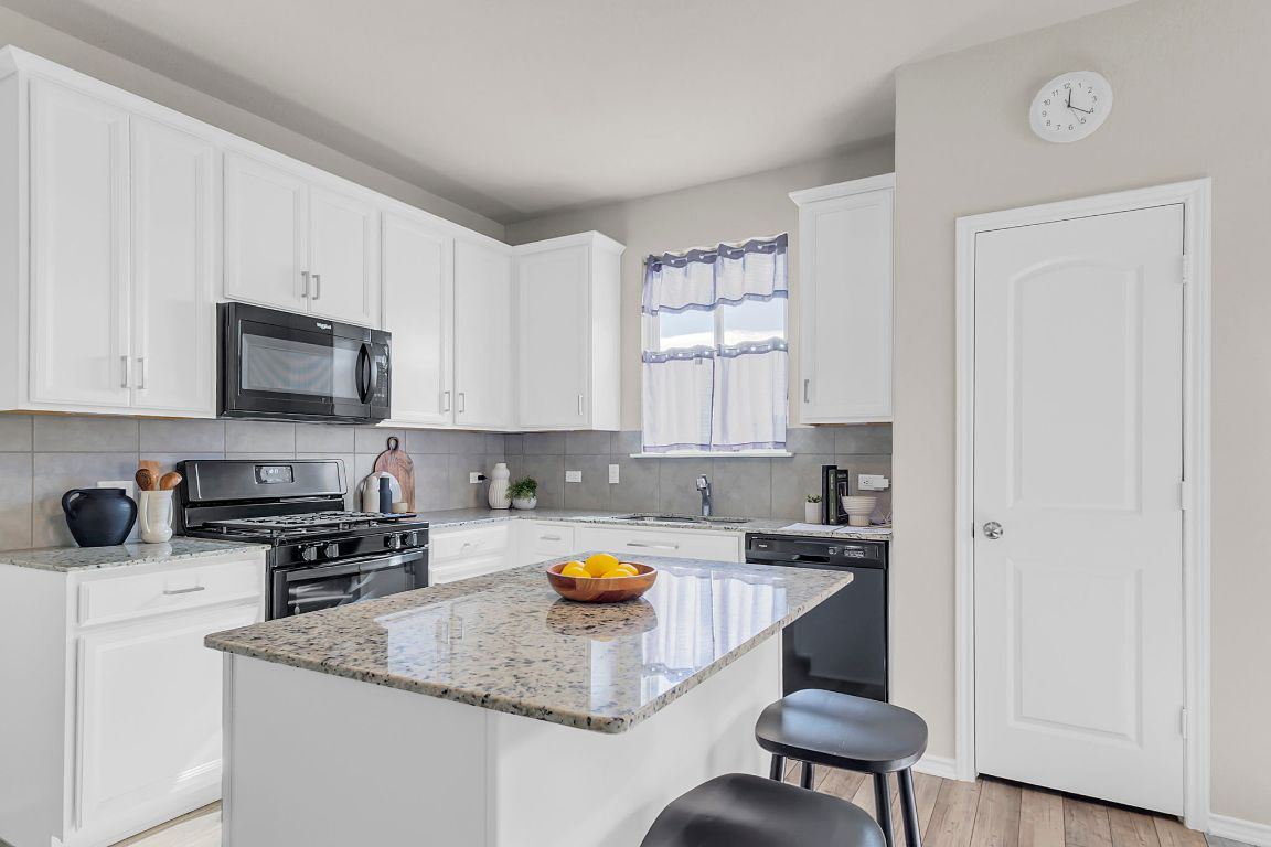 112 Black Alder Street Georgetown, TX 78626 - Photo 9 of 37 a kitchen with a sink a stove a microwave and cabinets