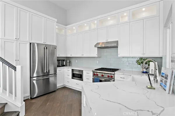 a kitchen with stainless steel appliances granite countertop a refrigerator a stove and a sink with wooden floor