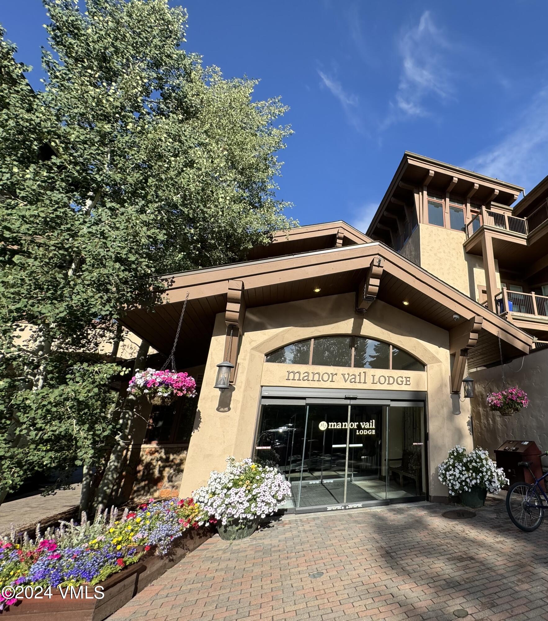 595 Vail Valley Drive, Unit E121 Vail, CO 81657 - Photo 10 of 12 a view of a house with a small yard and a large tree