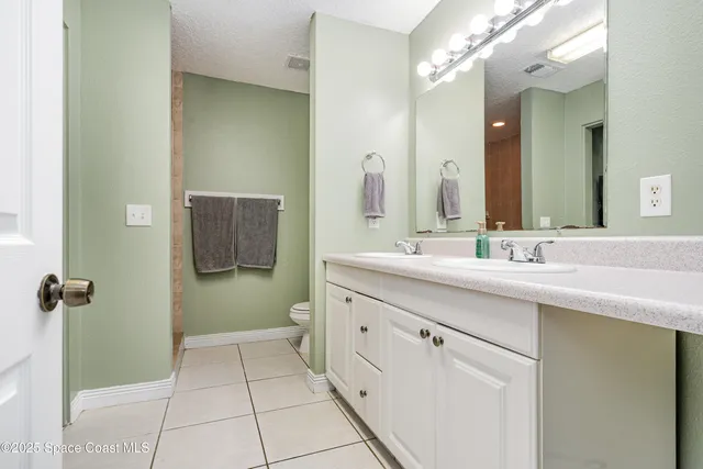 a bathroom with a double vanity sink a toilet and a mirror