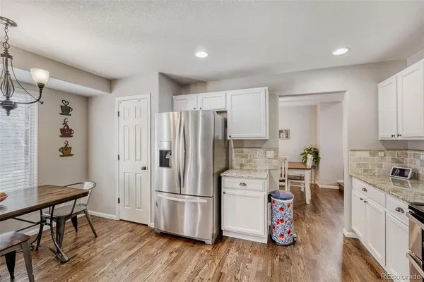 a kitchen with a refrigerator a stove and a wooden floor